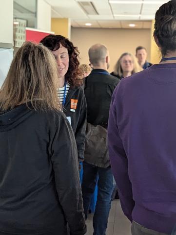 Group of 2024 NEDCamp attendees chatting in corridor between sessions.