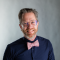 A headshot of James Sansbury, smiling and sporting a pink bowtie