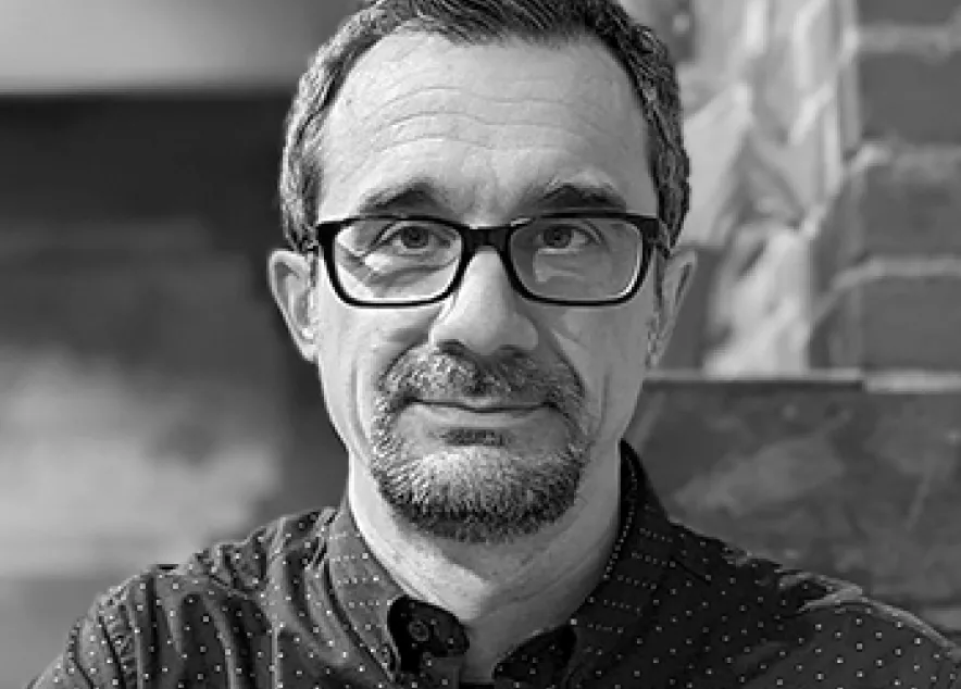 J. Hogue looking straight at the camera, dark short hair, glasses, and a beard and moustache