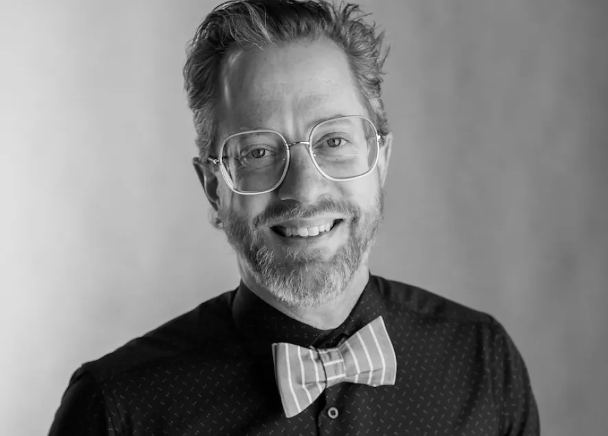 A headshot of James Sansbury, smiling and sporting a pink bowtie