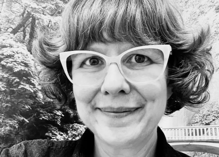 A middle-age woman with short wavy hair and cute glasses