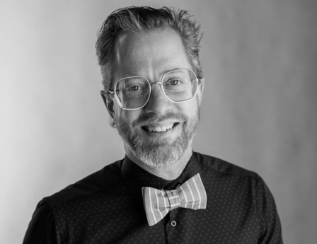 A headshot of James Sansbury, smiling and sporting a pink bowtie