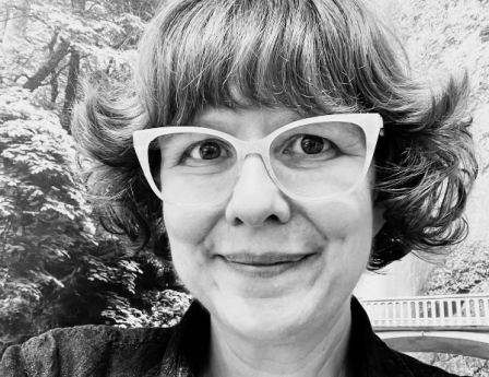 A middle-age woman with short wavy hair and cute glasses